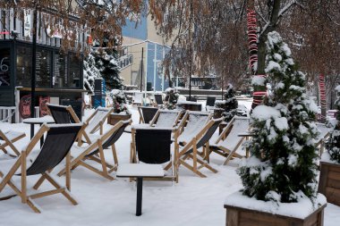 Büyüleyici ahşap sandalyeler taze karda huzur içinde oturur, kışın sıcaklığını hatırlatır..