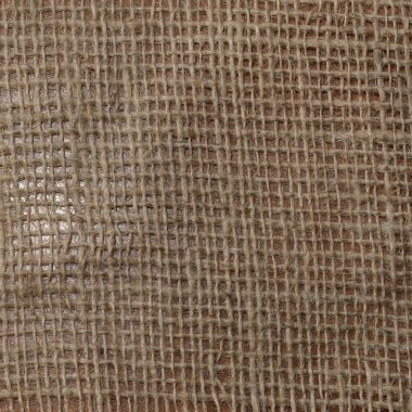 Işık, doğal dokusu ve sıcaklığını vurgulayarak, bir çuval bezi yüzeyinde hafifçe parlar..