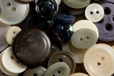 Çeşitli şekil ve dokuların renkli düğmeleri etrafa saçılmış..