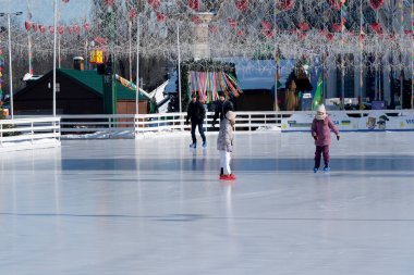 Ilık bir kış gününde parlak dekorasyonların altında çocuklar parlak buzların üzerinde süzülür. Kyiv, Ukrayna. 21 Şubat 2026. Ukrayna Ulusal Kompleks Expocenter, Maslenitsa