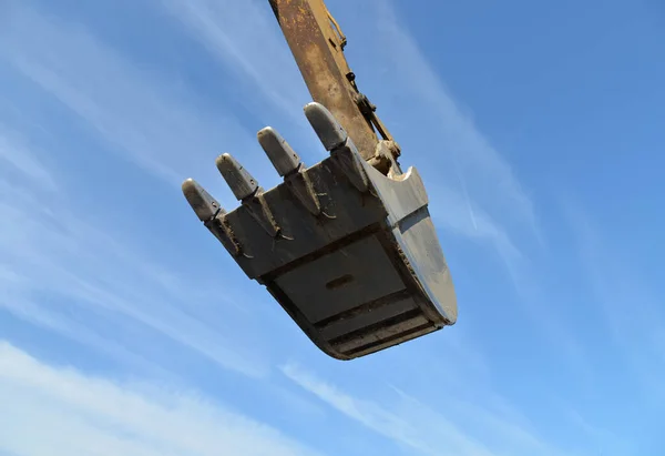 Industrial excavator bucket close up on blue sky