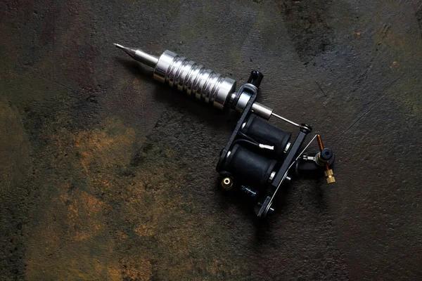 Dövme makinesi, paslı metal arka planda dövme silahı.