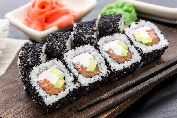 Rolo de sushi de salmão coberto com gergelim — Fotografia de Stock