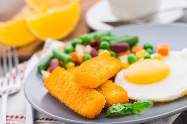 Palitos de peixe, ovo frito e legumes — Fotografia de Stock