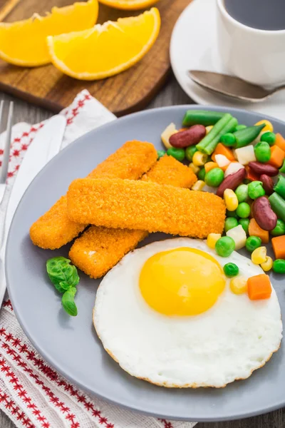 Fisk pinnar, stekt ägg och grönsaker — Stockfoto