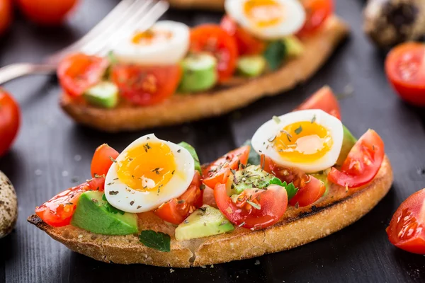 Bruschetta com tomate, abacate e ovo de codorna — Fotografia de Stock