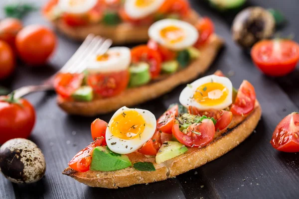 Bruschetta con pomodoro, avocado e uova di quaglia — Foto Stock