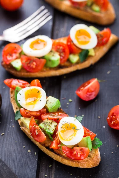 Bruschetta med tomat, avokado och vaktel ägg — Stockfoto