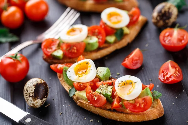 Bruschetta with tomato, avocado and quail egg — Stock Photo, Image