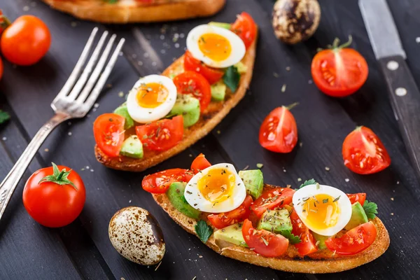 Bruschetta with tomato, avocado and quail egg — Stock Photo, Image