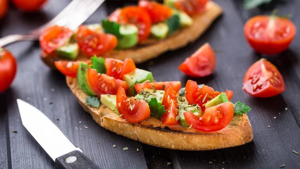 Bruschetta with tomato, avocado and herbs — Stock Photo, Image