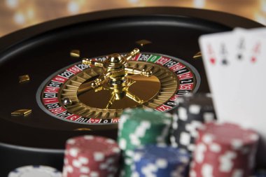 Kumar masasında poker fişleri, hareket halindeki rulet çarkı, kumarhane geçmişi