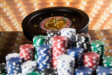 Kumar masasında poker fişleri, hareket halindeki rulet çarkı, kumarhane geçmişi