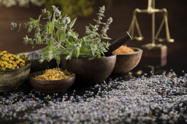 Homeopati, ahşap masada bitkisel ilaçlar, siyah ayna arka planı.