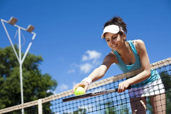Flickan står nära tennis rutnät på himlen — Stockfoto
