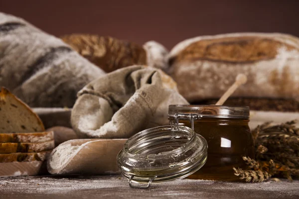 Freshly baked bread and jar of honey — Stock Photo, Image