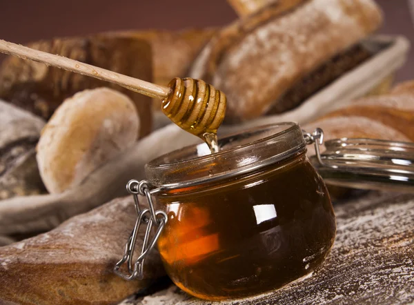 Pão fresco assado e pote de mel — Fotografia de Stock