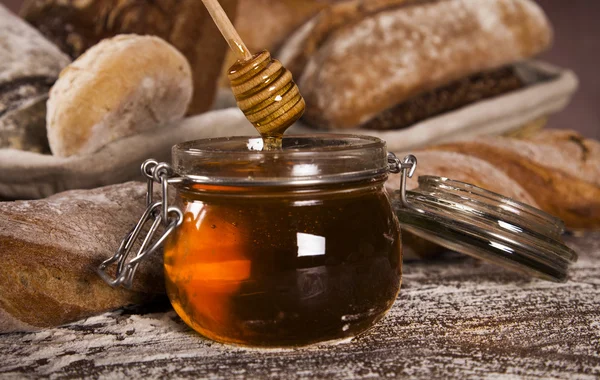 Freshly baked bread and jar of honey — Stock Photo, Image