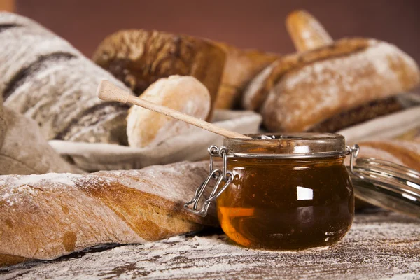 Frisch gebackenes Brot und ein Glas Honig — Stockfoto