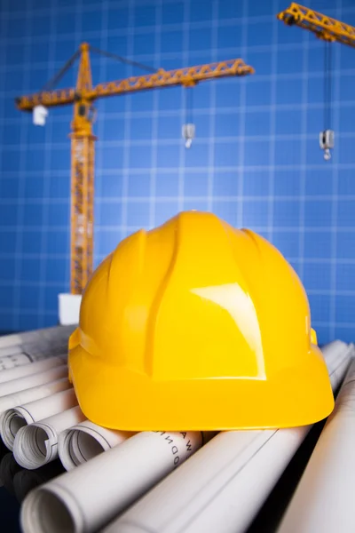 Stavební plán s jeřábem a žlutá helma — Stock fotografie