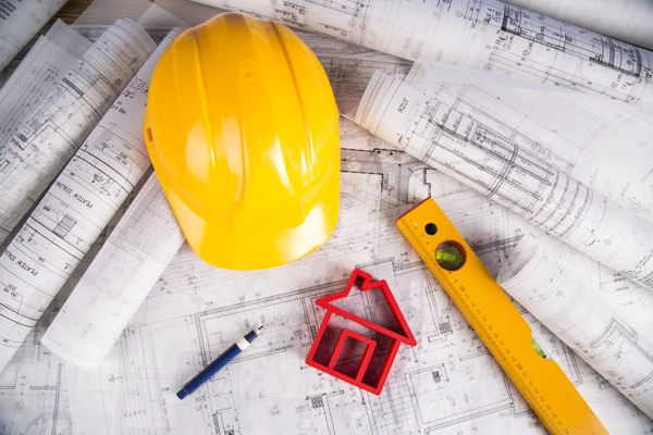 Capacete amarelo, desenhos de projeto e modelo de casa — Fotografia de Stock