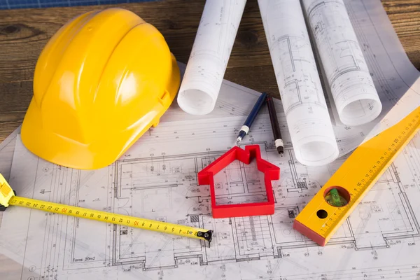 Capacete amarelo, desenhos de projeto e modelo de casa — Fotografia de Stock