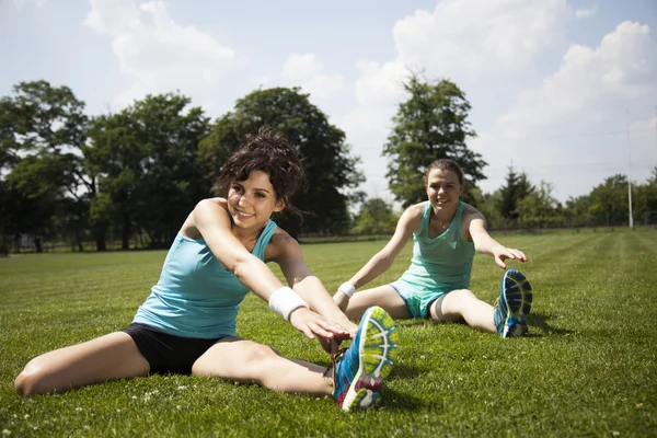 Femmes s'étirant assises sur de l'herbe verte — Photo