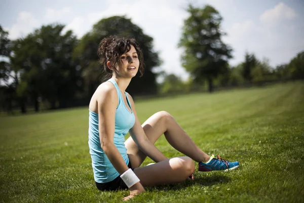 Sportovní žena odpočívá na zelené trávě — Stock fotografie