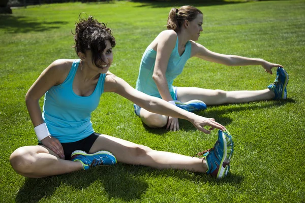 Femmes s'étirant assises sur de l'herbe verte — Photo