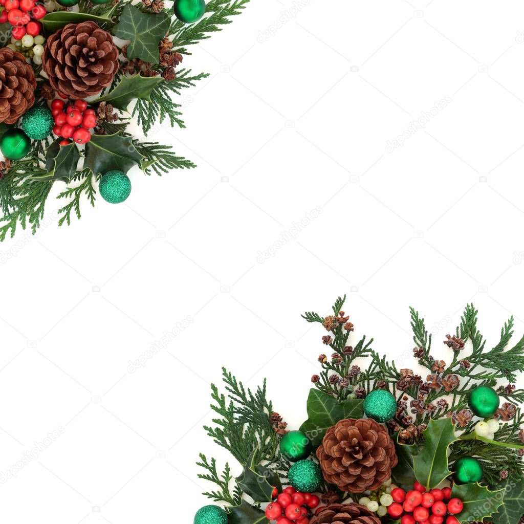 Christmas border with green baubles & winter greenery of holly, mistletoe, ivy, pine cones & cedar cypress fir on white. Xmas & New Year decorative background. Flat lay, top view, copy space.