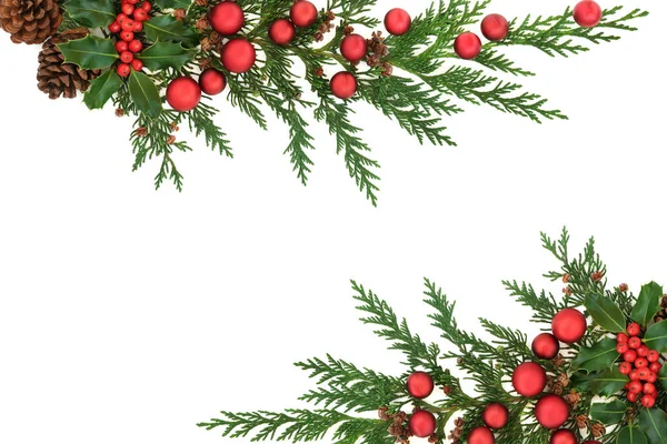白い背景にホリー 杉のヒノキ 松のコーンと赤の泡とクリスマスの背景の境界線 お祝いの季節のための装飾的なクリスマスデザイン フラットレイアウト トップビュー コピースペース — ストック写真