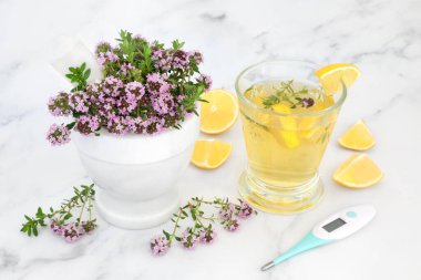 Doğal soğuk algınlığı ilacını limonlu termometre ve sıcak içecekle mermer harç ve tokmağında artırmak için kekik otu. Anti bakteriyel, antiseptik ve antiviral. Mermer arka planda.