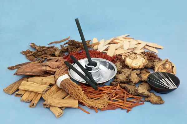 Chinese acupuncture needles &  moxa sticks used in moxibustion treatment with herbs & spice used in traditional herbal medicine. On mottled blue background. Alternative & holistic health care concept.