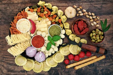 Eski dökme demir tava ve rustik ahşap arka planda İtalyan makarnası ve sağlıklı gıda malzemelerinin büyük bir koleksiyonu. Besleyici besinler yüksek iyon antioksidanlar, antosiyaninler, omega 3, protein, fiber & likopin. Düz yatıyordu.