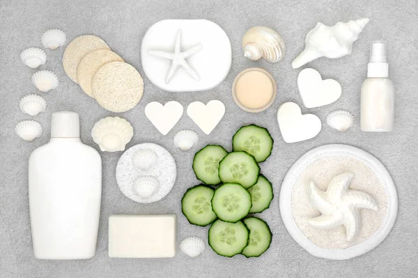 Natural organic beauty treatment products for skin care with cucumber, soaps, moisturizer, cleansing sponges and ex foliation scrub, decorative seashells. Flat lay.