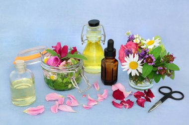 Aromaterapi, yaz bitkileriyle ve yağ aşılama için çiçeklerle gerekli yağ hazırlığıdır. Naturopatik bitki tıbbı için sağlık hizmeti konsepti. Benekli mavi arka planda hayat devam ediyor.