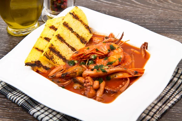 Fish soup with grilled polenta on white dish — Stock Photo, Image