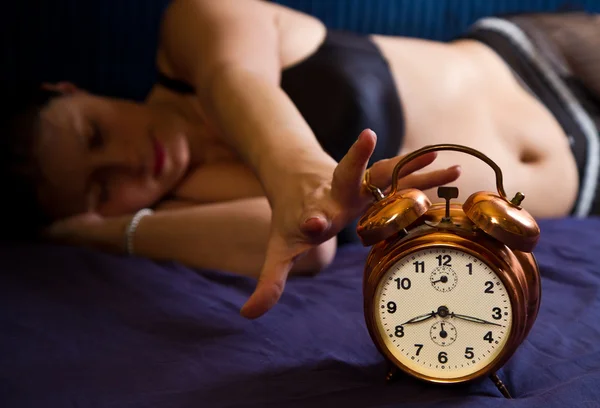 Красивая молодая женщина просыпается с будильником — стоковое фото