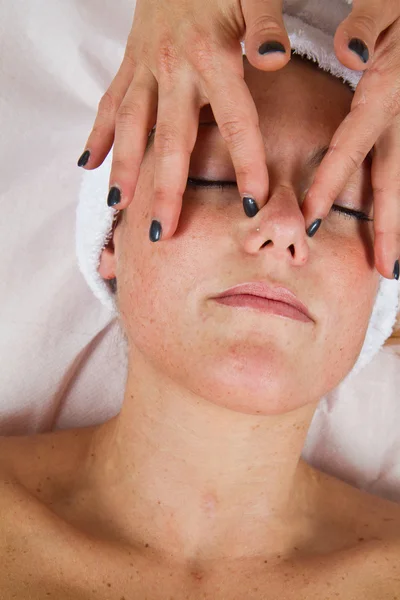 Mooie jonge vrouw gezicht massage met gesloten ogen ontvangen — Stockfoto
