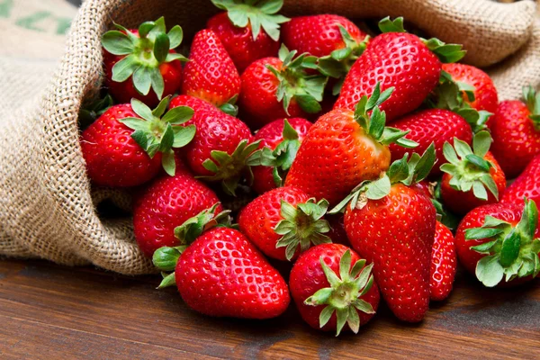 Fresh strawberry in burlap sack on wood — Stock Photo, Image