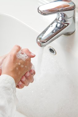 Kadın ellerini sabunla yıkıyor. 