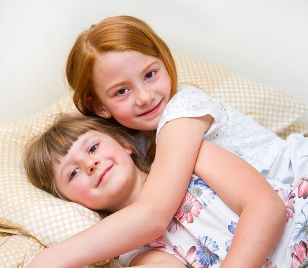 Dois feliz menina abraçando na cama — Fotografia de Stock