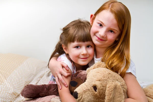 Lilla vän embracing togetherteddy Björn i sängen — Stockfoto