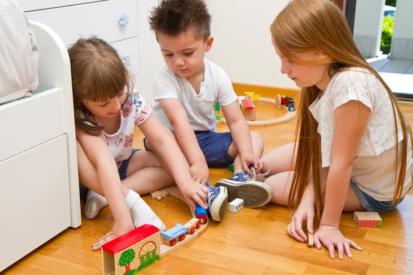 Little Children playing with wooden train in the room — Stock Photo, Image