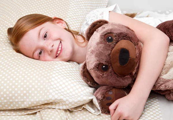 Kleines Mädchen im Bett umarmt den Teddybär lizenzfreie Stockfotos