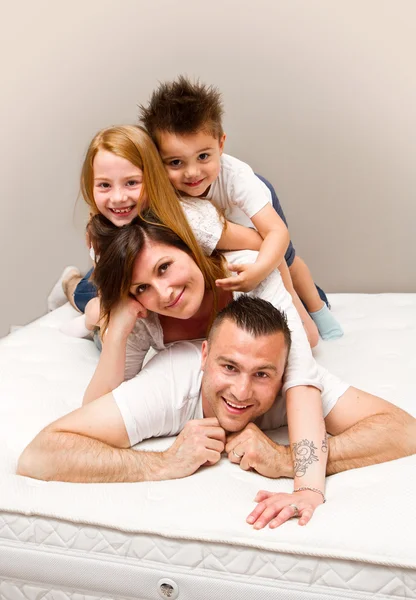 Famille souriante s'amuser allongé sur le lit — Photo