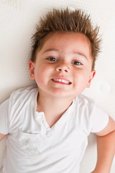 小男孩坐在大量的床垫，白色背景上孤立 — 图库照片