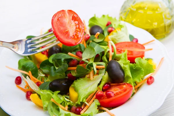 Gemischter Salat mit Tomaten in weißem Teller auf Holztisch — Stockfoto