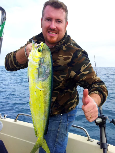 Pescador segurando um peixe golfinho — Fotografia de Stock