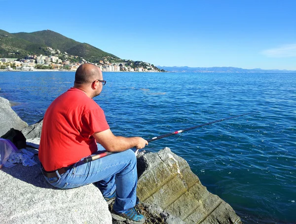 Pescador pesca sobre a rocha — Fotografia de Stock